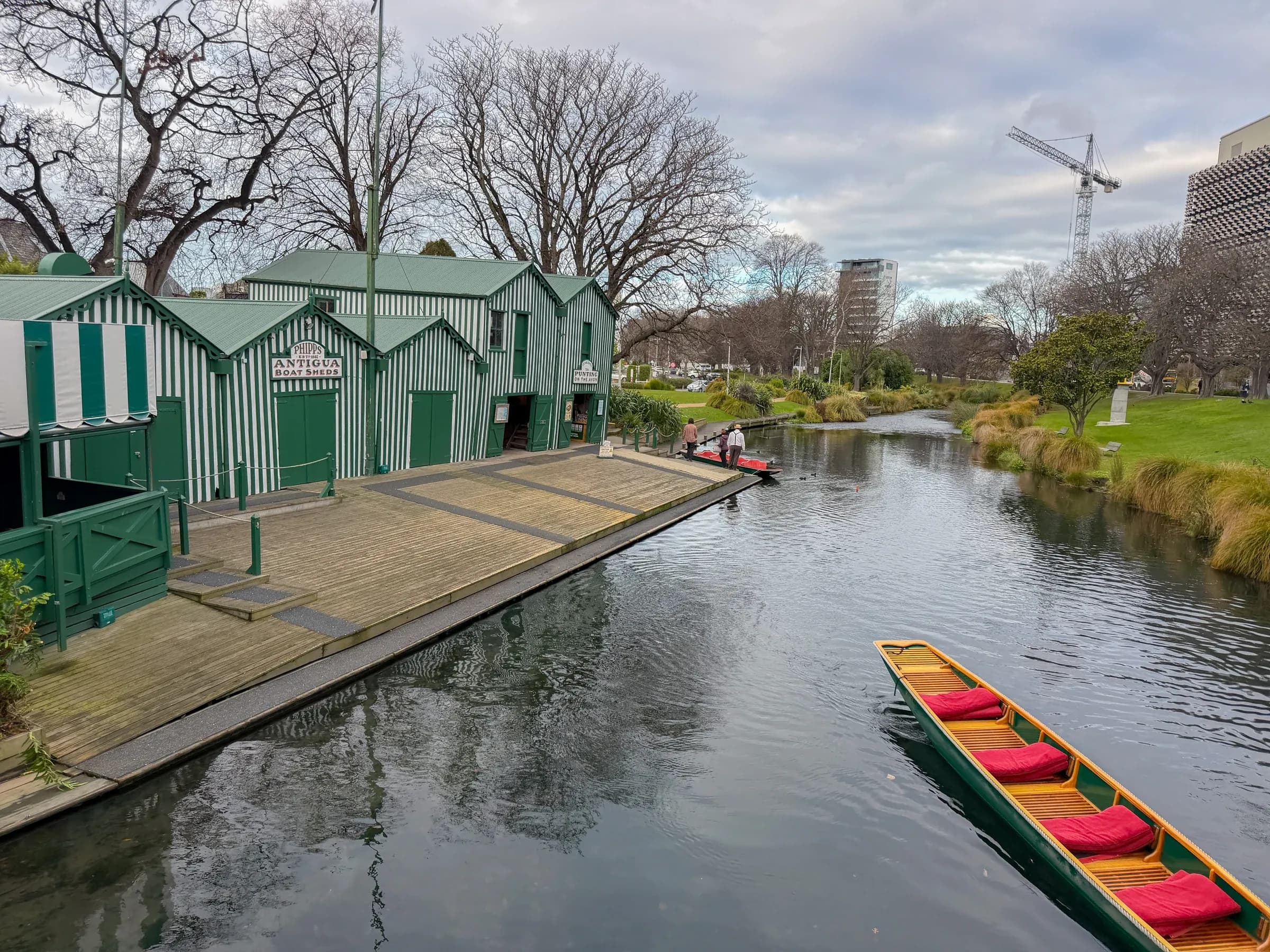 A red-cushioned punt beside the striped Antigua Boatsheds.